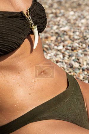 Foto de Primer plano del vientre femenino durante el tomar el sol en la playa de guijarros - Imagen libre de derechos