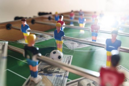 Foto de Juego de futbolín con billetes de dólar esparcidos a su alrededor, aludiendo a un concepto de apuesta y victoria - Imagen libre de derechos