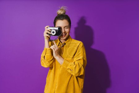 Téléchargez les photos : Portrait de jeune fille gaie avec appareil photo de film sur fond violet - en image libre de droit