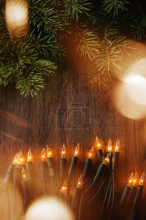 Foto de Superficie de madera adornada con luces de Navidad centelleantes y ramitas de abeto fresco. - Imagen libre de derechos