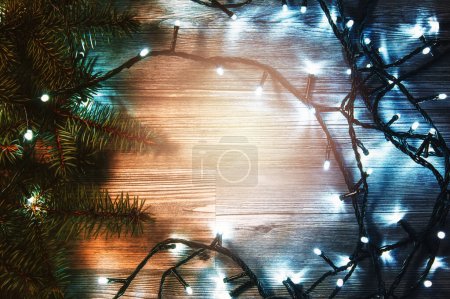 Téléchargez les photos : Surface en bois ornée de lumières de Noël scintillantes et de brindilles d'épinette fraîches. - en image libre de droit