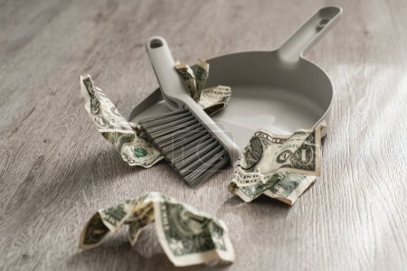 Foto de Sartén y cepillo junto a billetes dispersos de un dólar en el suelo. - Imagen libre de derechos