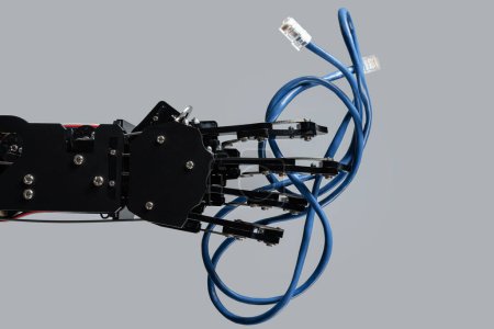 Foto de La mano del robot real sostiene el cable Ethernet azul con conector rj45 sobre fondo gris. - Imagen libre de derechos