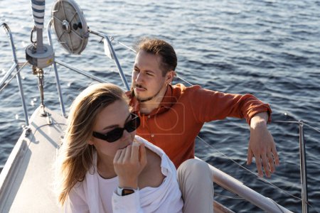 Photo for Young attractive couple relaxing on the sailboat during sailing in the sea. - Royalty Free Image