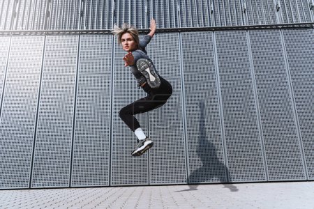 Photo for Woman athlete jumping like kung fu fighter on the street - Royalty Free Image