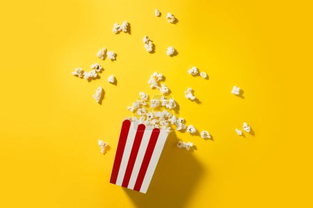 Photo for Classic striped bucket with delicious popcorn on  yellow background. - Royalty Free Image