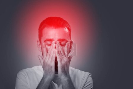 Téléchargez les photos : Jeune homme souffrant de migraine maux de tête et tenir sa tête avec les mains - en image libre de droit