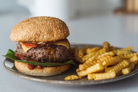 Photo for Delectable homemade cheeseburger on a plate accompanied by golden crispy French fries. - Royalty Free Image