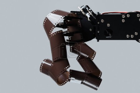 Real robotic hand with film stock. Concept of AI in motion picture and photography industry.