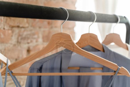 Photo for Closeup of wooden hangers with different outfits in the wardrobe - Royalty Free Image
