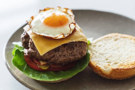 Téléchargez les photos : Délicieux cheeseburger maison garni d'un oeuf parfaitement frit et ensoleillé. - en image libre de droit