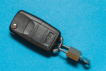 Foto de Candado con llave en el interior unido a las llaves de un coche negro en bkacground azul - Imagen libre de derechos