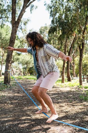Photo for Confident young man slacklining in the city park during summer day - Royalty Free Image
