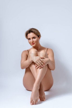 Téléchargez les photos : Jeune femme attrayante portant de la lingerie brune est heureuse avec son corps et sa peau lisse. - en image libre de droit