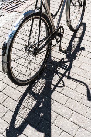 Photo for Iron road bicycle on a city street, casting a shadow in the sunlight with no people around. - Royalty Free Image
