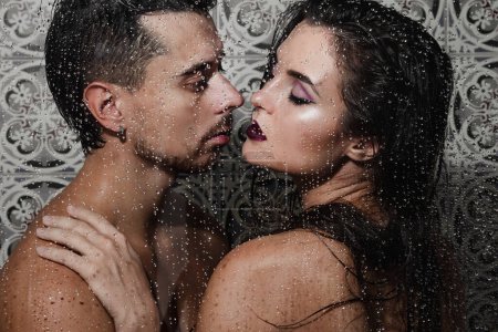 Téléchargez les photos : Portrait de couple beau et sensuel capturé à travers le verre mouillé - en image libre de droit