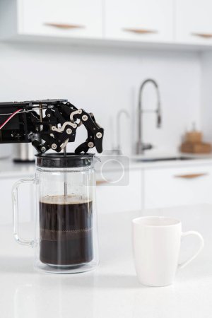 Téléchargez les photos : Véritable main de robot et presse française au café noir. Concept d'automatisation robotique des processus. - en image libre de droit