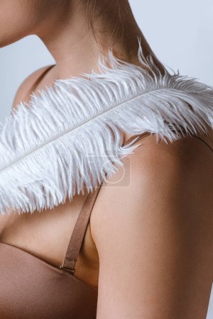 Foto de Cuerpo femenino y pluma suave. Conceptos de cosméticos corporales y tratamiento de depilación. - Imagen libre de derechos