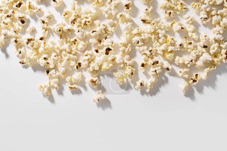 Téléchargez les photos : Popcorn dispersé sur fond blanc avec éclairage dur. - en image libre de droit