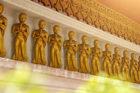 Téléchargez les photos : Rangée de statues de Bouddha d'or, chacune dans une posture de prière, située dans un ancien temple thaïlandais crée une atmosphère puissante et spirituelle. - en image libre de droit