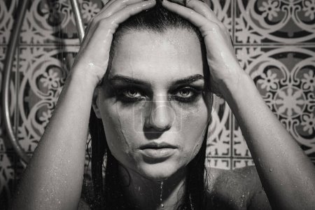 Foto de Retrato monocromático de mujer triste y húmeda con maquillaje manchado en su cara bajo la ducha - Imagen libre de derechos