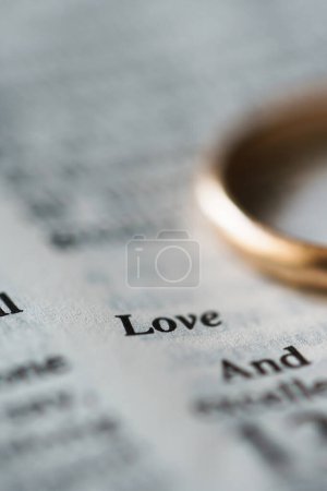 Téléchargez les photos : Gros plan de l'alliance d'or et des pages ouvertes de la bible sainte représente le concept de mariage et l'amour entre deux chrétiens - en image libre de droit