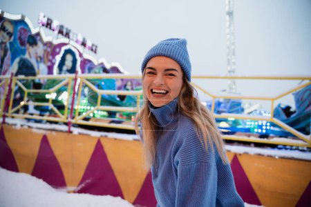 Téléchargez les photos : Femme gaie et élégante, vêtue de vêtements chauds, s'amuse dans un parc d'attractions hivernal enneigé. - en image libre de droit