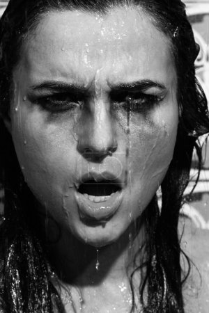 Téléchargez les photos : Portrait monochrome de femme triste et humide avec un maquillage maculé sur le visage sous la douche - en image libre de droit