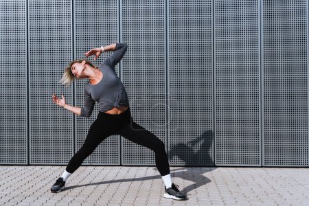 Foto de Bailarina expresiva que actúa contra el fondo con paneles de acero modernos. - Imagen libre de derechos