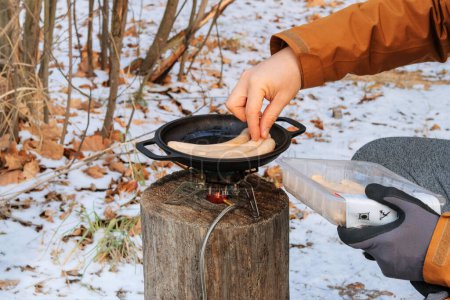 Téléchargez les photos : Aliments touristiques dans les activités de plein air. Saucisses au bowler dans la forêt en hiver. Camping fabrication de nourriture. - en image libre de droit