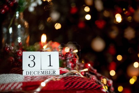Photo for December 31 calendar against the background of a Christmas tree with decor and candles in red. idea happy new year and christmas 202 - Royalty Free Image
