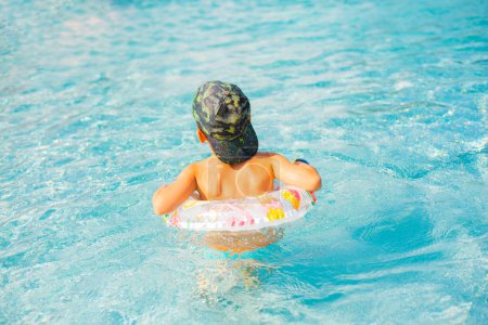 Téléchargez les photos : Enfant garçon nageant dans la piscine bleue.Enfant souriant en vacances dans la piscine - en image libre de droit