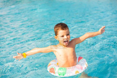 Téléchargez les photos : Enfant garçon s'amusant dans la piscine.Enfant souriant en vacances dans la piscine - en image libre de droit
