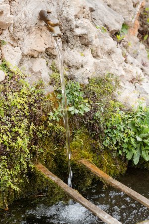 Foto de Fuente de agua dulce sobre el arroyo en el jardín de la Abadía de Gellone en el famoso pueblo de Saint Guilhem le Desert protegido por la UNESCO, Francia - Imagen libre de derechos