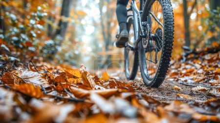 Close perspective of a mountain bike tire rolling over crisp autumn leaves on a forest trail, evoking the essence of fall cycling