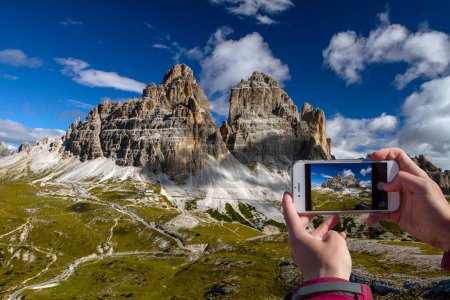 Foto de Un teléfono en la mano de una mujer tomando fotos de montañas. Dolomitas. Cordillera de los Alpes Orientales. El macizo está situado en la parte noreste de Italia.Los Dolomitas son una zona popular para el turismo y los deportes de invierno.. - Imagen libre de derechos