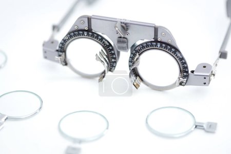 Nahaufnahme des Augentestrahmens für Optiker mit vielen verschiedenen Versuchslinsen zum Augenschutz vor weißem Hintergrund