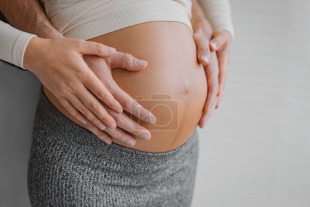 Pregnancy photo man and woman holding pregnant bump expecting baby. Happy family hands on stomach closeup. Couple in love.