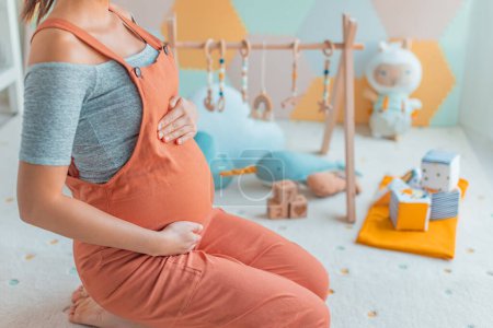 Schwangere Bauch mit Baby-Aktivität Turnhalle spielen, Spielzeug und Spielmatte im Kinderzimmer oder Spielzimmer. Schwangerschaftskonzept und Wohnraumplanung und Dekorationskonzept Foto.