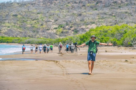 Galapagos tourisme groupe de photographes de voyage de touristes en croisière randonnée sur la plage de la baie d'Urbina, île Isabela, Islas Galapagos destination Équateur.