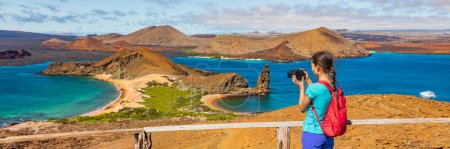 Galapagos islands ecotourism travel banner. Bartolome Island, tourist hiking in the Islas Galapagos archipelago. Panoramic view of Sullivan bay, golden beach and Santiago island on cruise excursion.
