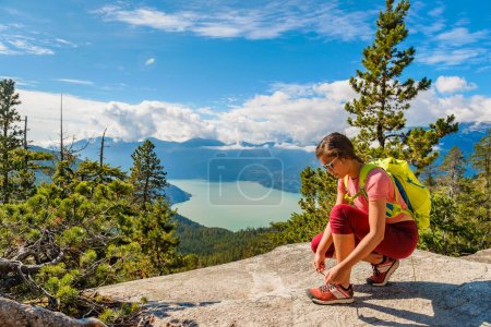 Trail Runner Wanderin schnürt Schnürsenkel auf Trail Run und Wanderung. Erfolgreiche Frau, die ein gesundes, aufstrebendes Outdoor-Leben führt, macht Pause beim Trailrunning und in Squamish, British Columbia, Kanada.