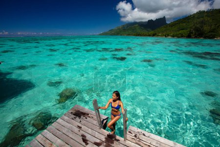 Luxus-Strandurlaub Frau in Tahiti Overwater Bungalow Hotel Villa schwimmen. Dieses Bild ist völlig unretuschiert und unbearbeitet und das Modell ist ungeschminkt. Ursprüngliches Rohbild.