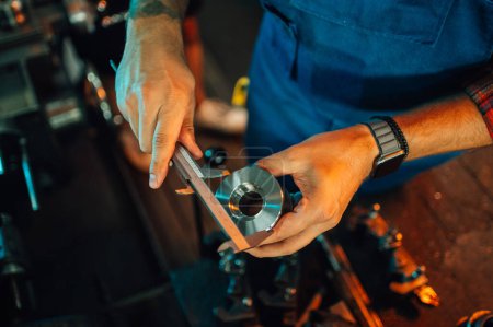Photo recadrée se concentrant sur les mains métallurgistes mesurant un élément de machine de découpe de rouleau métallique avec un étrier. Mesure du diamètre extérieur. Focus sur les mains mesurant la partie métallique. Usine.