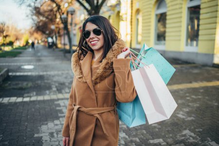 Fröhliche junge hispanische Frau mit Einkaufstüten in der Stadt