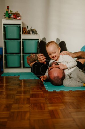 Un niño adorable está jugando un divertido juego de lucha libre con su padre. Un padre divirtiéndose con su amado hijo en casa. Una familia feliz está jugando juegos divertidos en casa juntos. Una educación saludable.