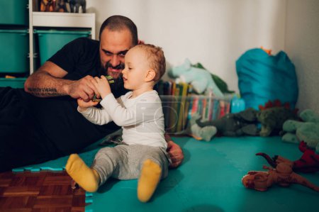 A fun dad is babysitting his beloved son while playing games and entertaining him with dinosaur toys. Imagination and healthy upbringing. A father is playing fun games with toys with his son.