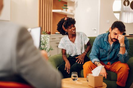 Portrait d'un couple diversifié essayant de résoudre certains problèmes dans leur relation. Les épouses qui accouchent parlent devant un thérapeute au cabinet d'un thérapeute. Concentrez-vous sur une femme afro-américaine. Espace de copie.