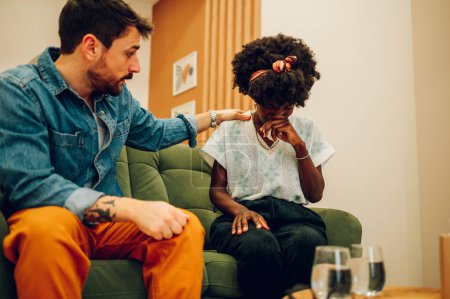Young diverse couple trying to solve some issues in their relationship. Multiracial spouses talking in front of a therapist at a therapist's office. Focus on a black woman with afro hair crying.