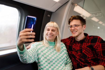 Portrait d'un ami heureux ou d'un couple s'amusant avec un smartphone et prenant un selfie en métro. Concept de relation avec les jeunes utilisant le téléphone dans une zone souterraine de la ville et prenant des photos.